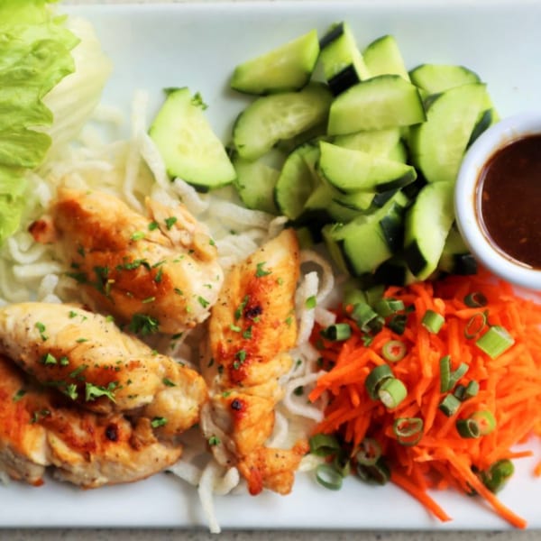 Grilled chicken tenders with shredded carrots, sliced cucumbers, lettuce, and dipping sauce.